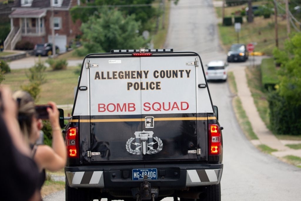 Allegheny County Police Bomb Squad truck seen driving on a residential street, with onlookers photographing the scene
