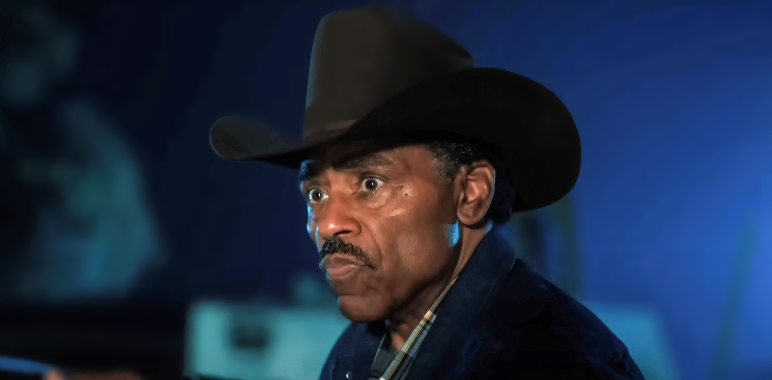Richard Lawson wearing a cowboy hat, looking ahead with a serious expression