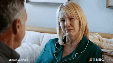 A woman in a green pajama top is making a puzzled expression while talking to a man. Text reads "#CHICAGOFIRE" and "NBC"