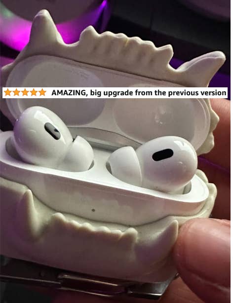 Person holding AirPods in a monster-themed case with a positive review mentioning, "AMAZING, big upgrade from the previous version."