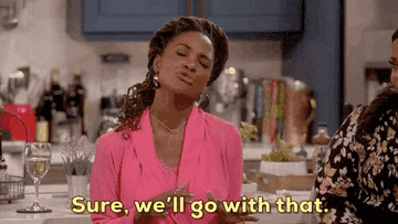 A woman in a kitchen gestures with her hands while speaking. Subtitles read: "Sure, we'll go with that."