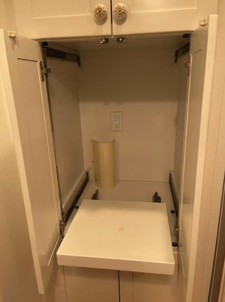 Open cupboard with a fold-out ironing board and an outlet on the wall