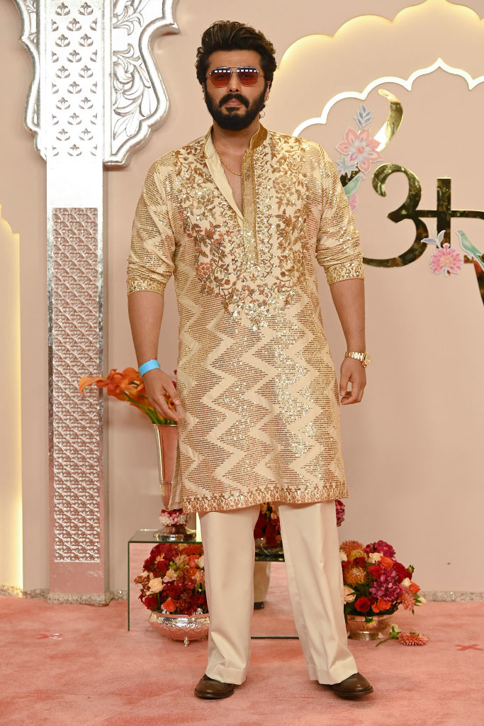 Arjun Kapoor in patterned kurta with floral designs and sunglasses on a decorated stage with floral arrangements