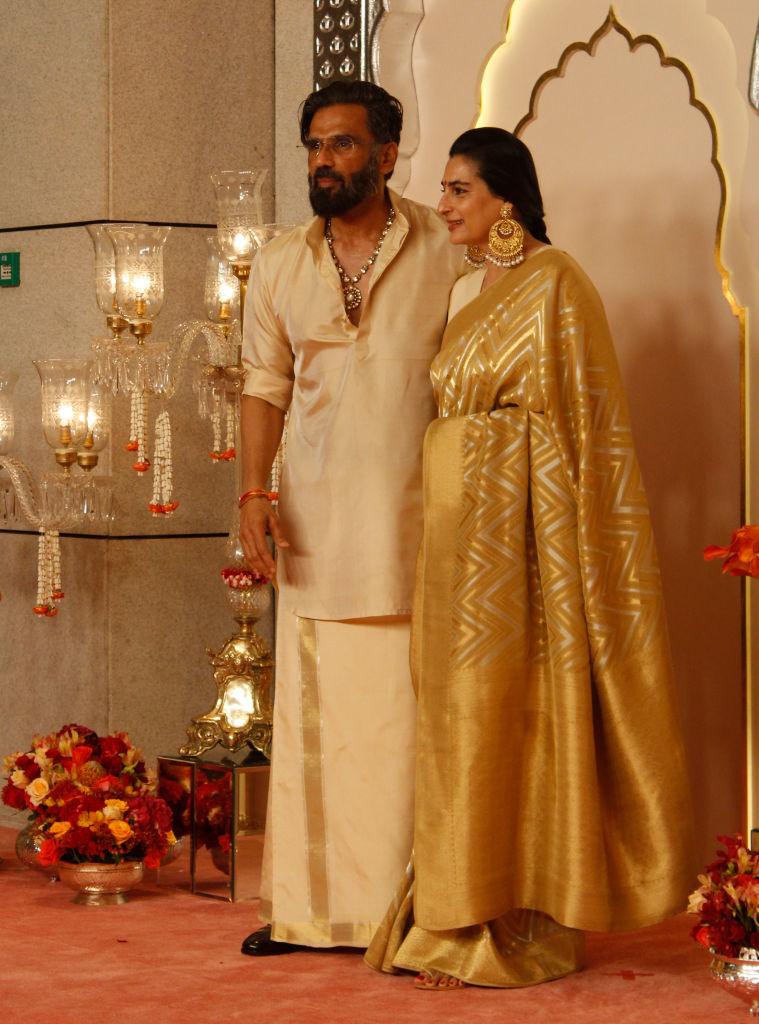 Suniel Shetty in traditional attire and Mana Shetty in an elegant sari pose together at an event