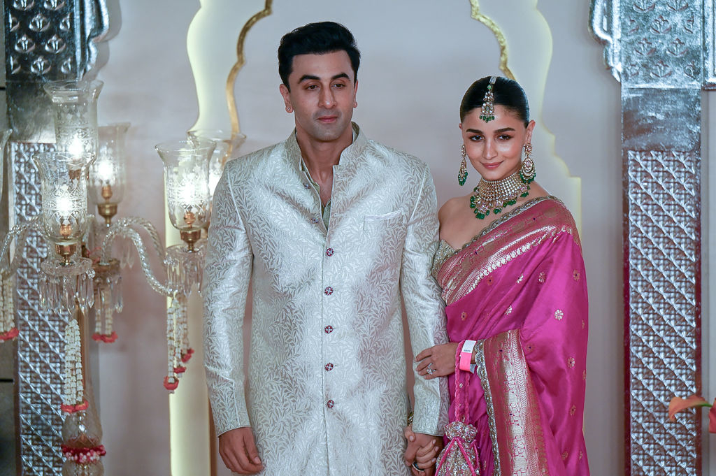 Ranbir Kapoor and Alia Bhatt at an event; Ranbir in a traditional embroidered jacket and Alia in a sari with intricate jewelry