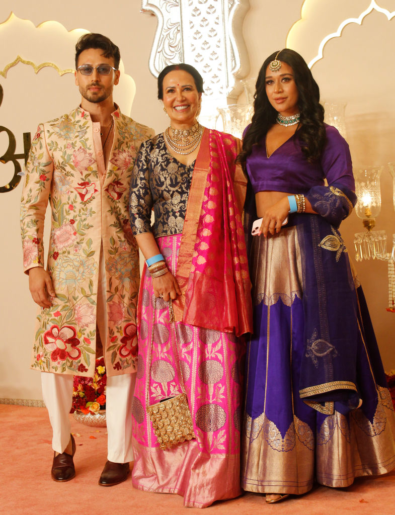 Tiger Shroff, Ayesha Shroff, and Krishna Shroff at an event. Tiger wears a floral embroidered sherwani; Ayesha wears a silk saree; Krishna wears a lehenga