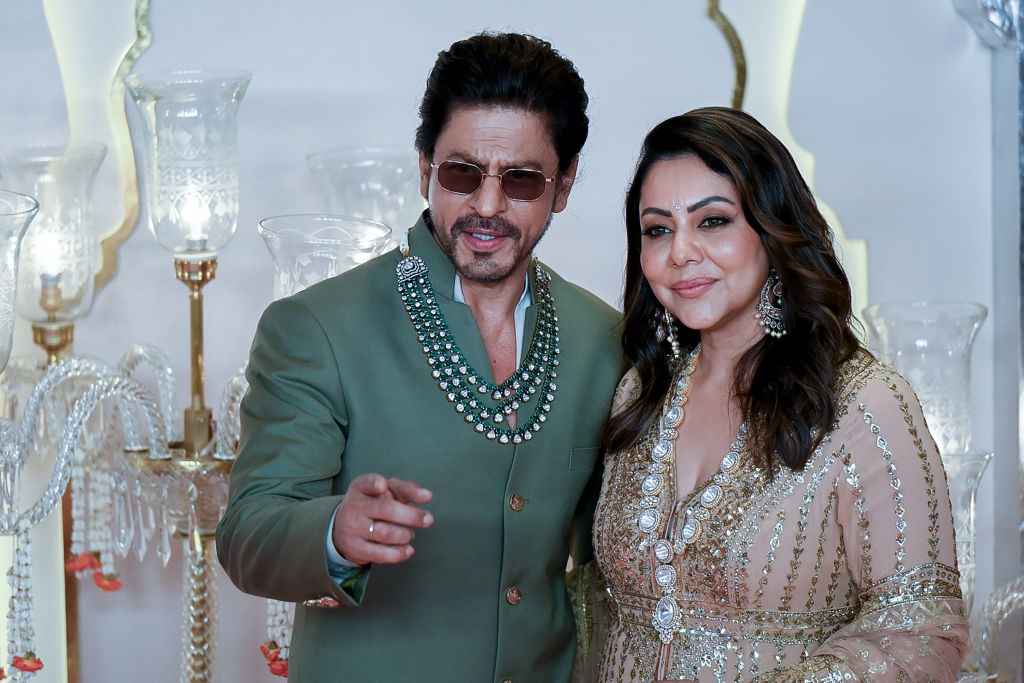 Shah Rukh Khan and Gauri Khan pose together. Shah Rukh wears a beaded suit, and Gauri wears a shimmering dress with detailed embroidery