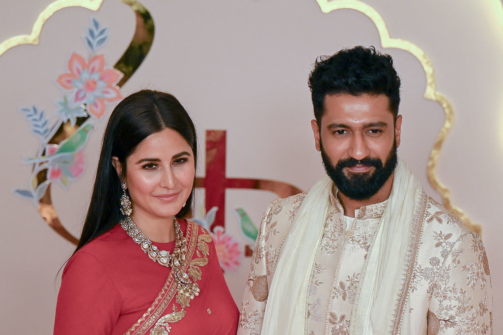 Katrina Kaif and Vicky Kaushal at an event. Katrina wears an ornate dress and necklace, while Vicky dons a traditional embroidered sherwani
