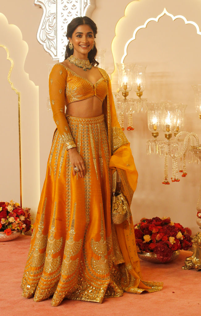 Pooja Hegde poses on a red carpet wearing an ornate traditional outfit with intricate patterns