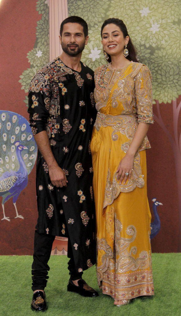 Shahid Kapoor and Mira Rajput on a carpet, dressed in traditional Indian attire. Shahid wears an embroidered kurta, and Mira wears ornate outfit