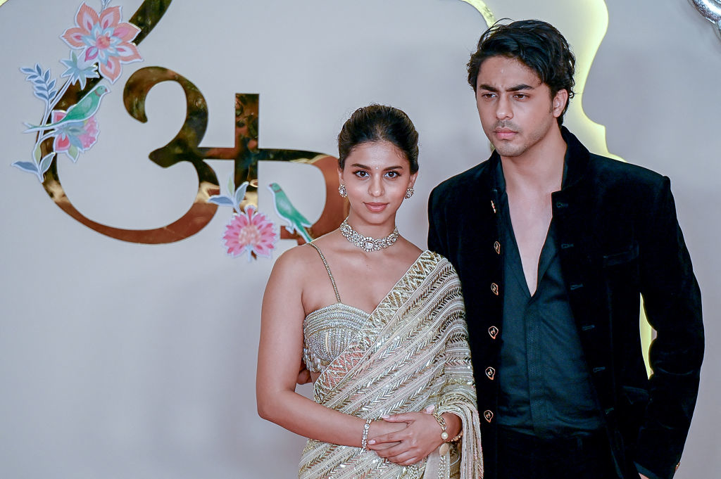 Suhana Khan in a shimmering sari and diamond jewelry, and Aryan Khan in a dark velvet suit, pose together at a glamorous event