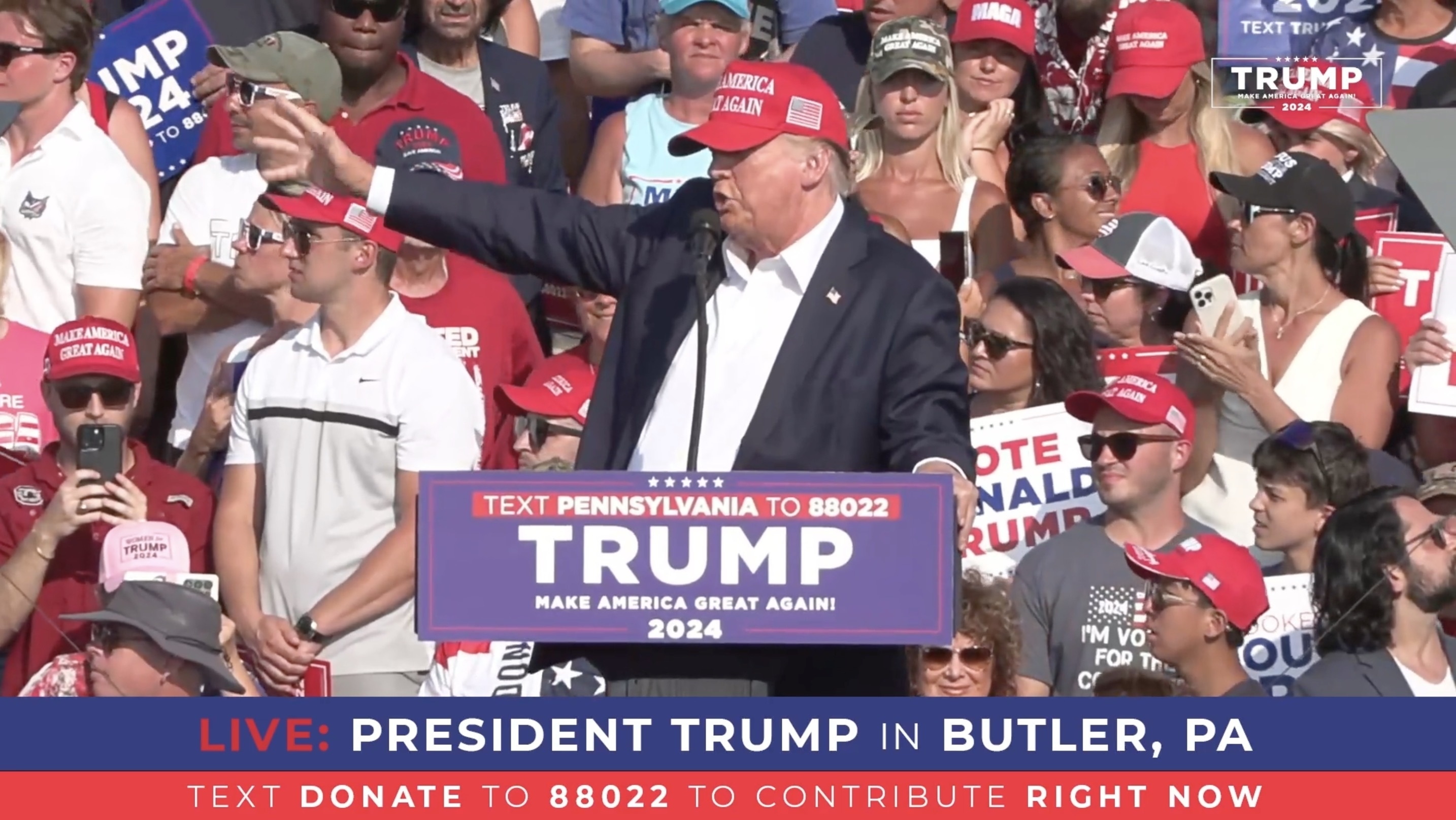 President Donald Trump speaks at an outdoor rally in Butler, PA, surrounded by supporters holding signs and wearing Trump campaign merchandise