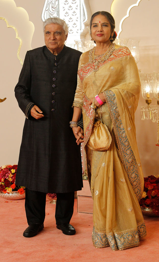Javed Akhtar and Shabana Azmi pose on the red carpet. Javed wears a traditional outfit, and Shabana wears an elegant saree with intricate details and jewelry