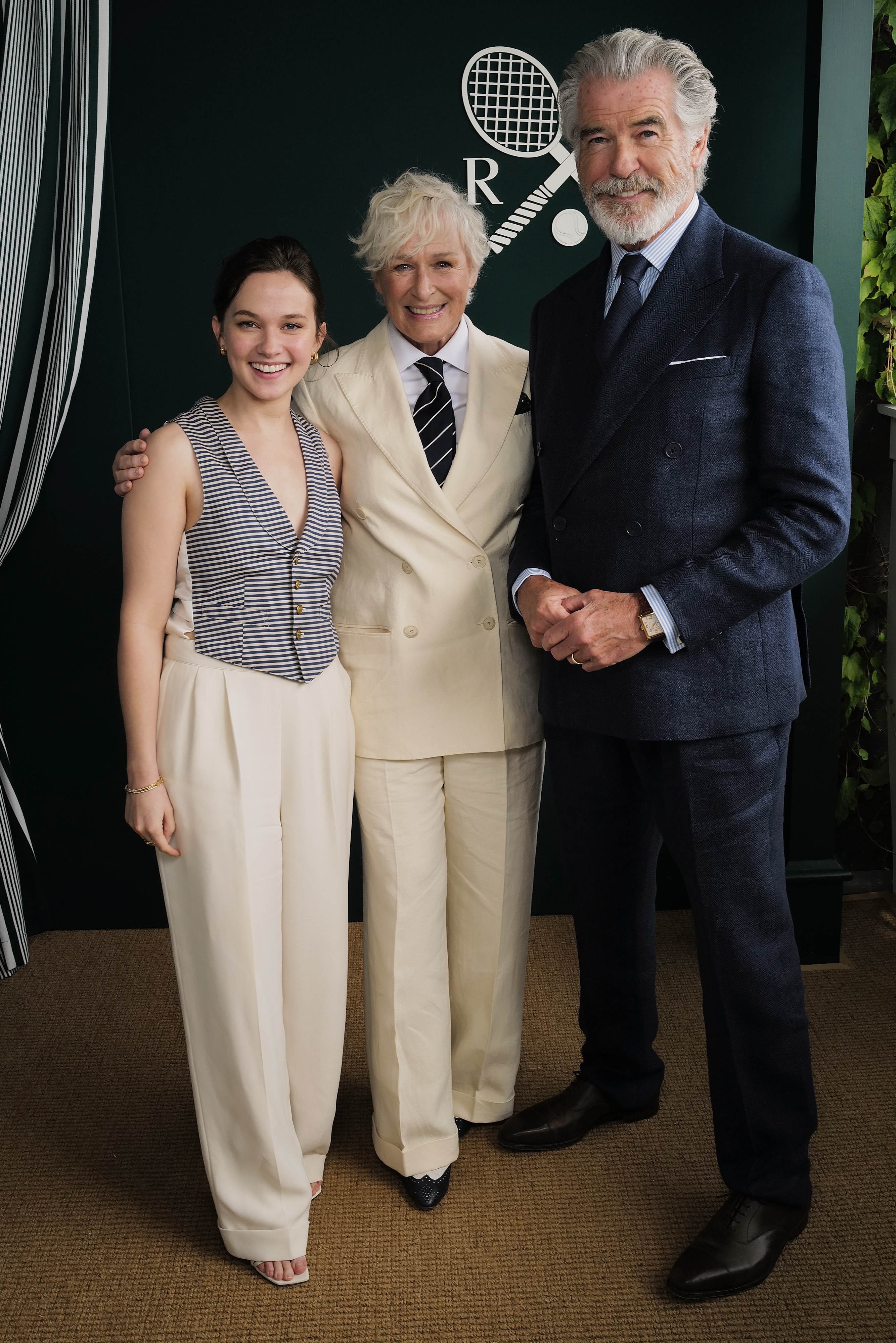 Pierce Brosnan, Glenn Close in a light suit, and Cailee Spaeny pose together at an event