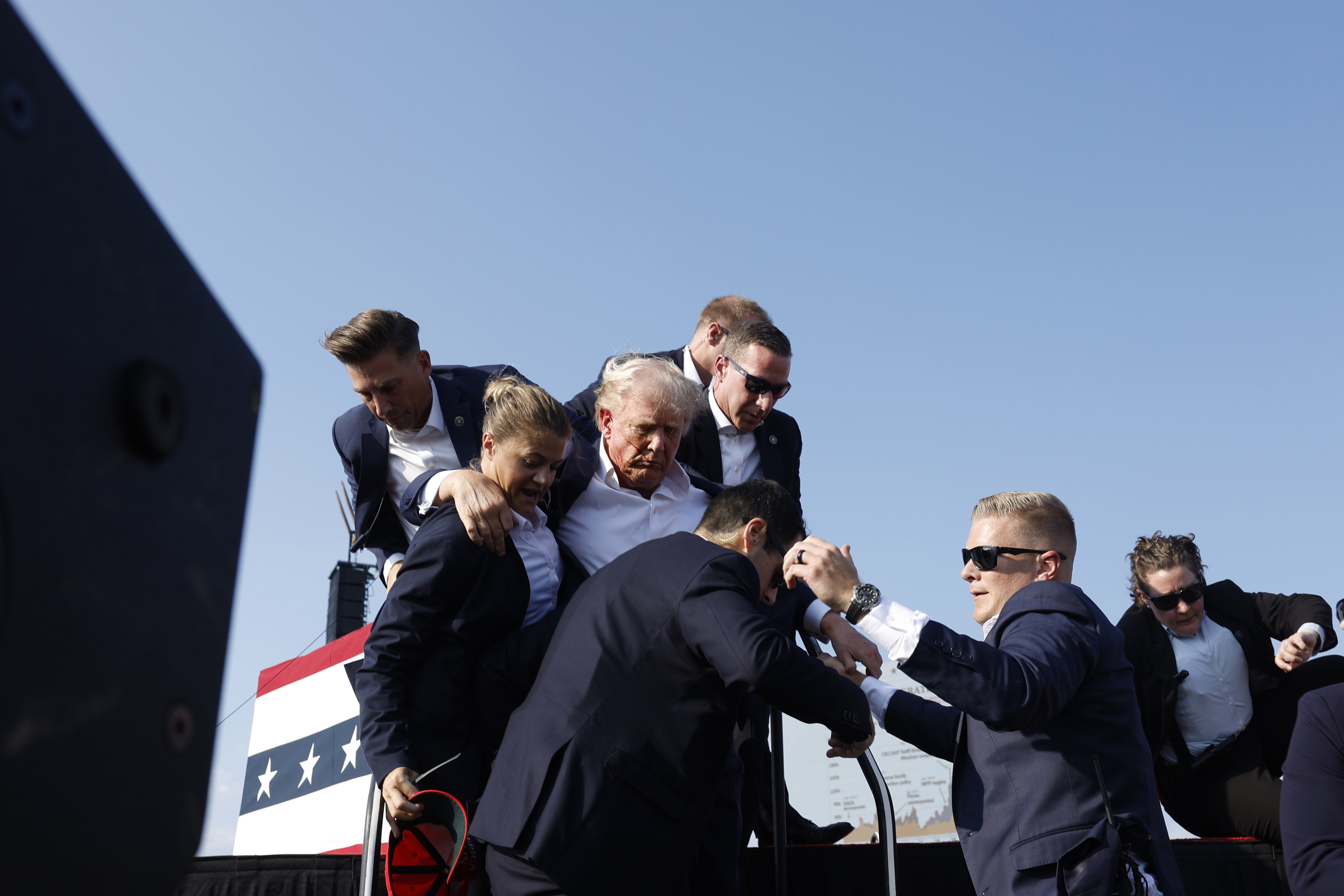 Donald Trump being escorted offstage by Secret Service agents following his assassination attempt