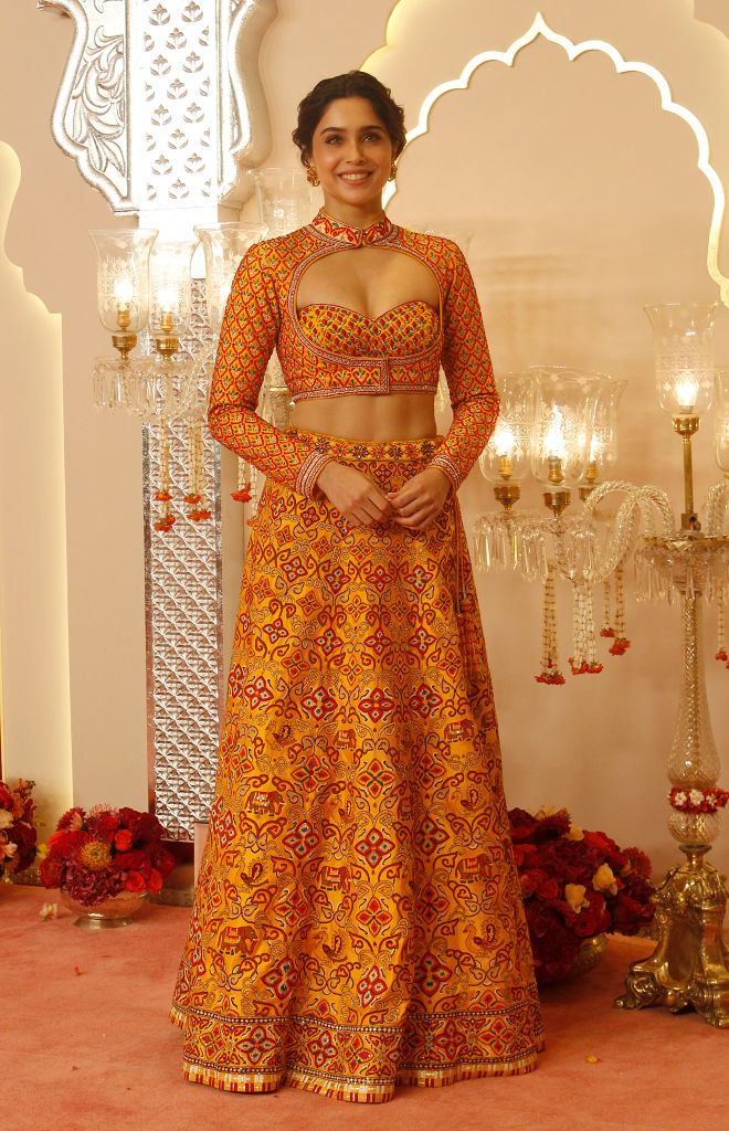 Sharvari Wagh in a stylish patterned outfit poses in front of ornate decor and chandeliers at an event