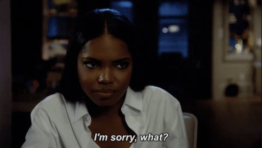A woman with long hair wearing a white shirt sits at a table, looking at someone with a surprised expression. Text on the image reads, &quot;I'm sorry, what?&quot;