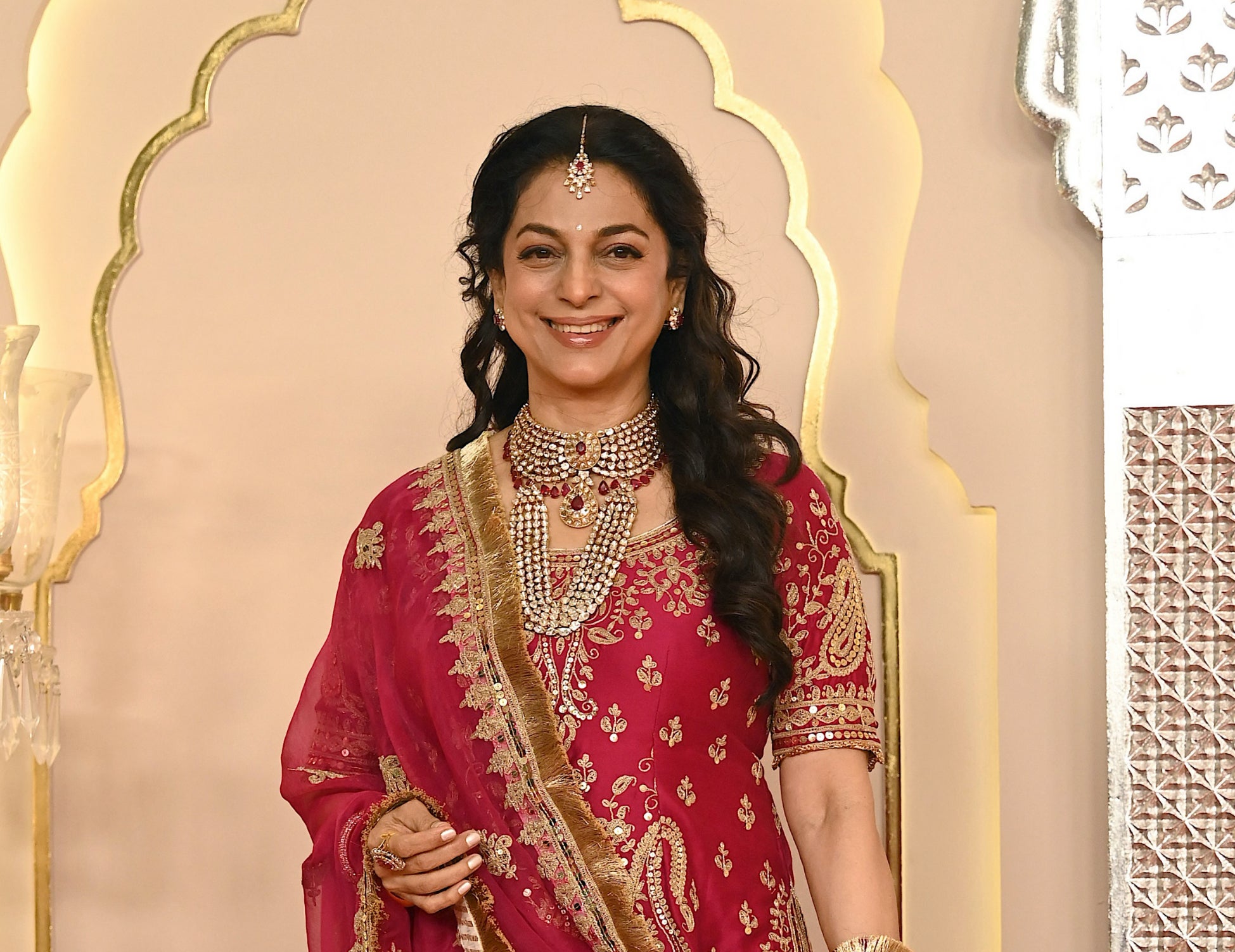 Juhi in an intricately embroidered traditional outfit, with elaborate jewelry, posing on a decorated set
