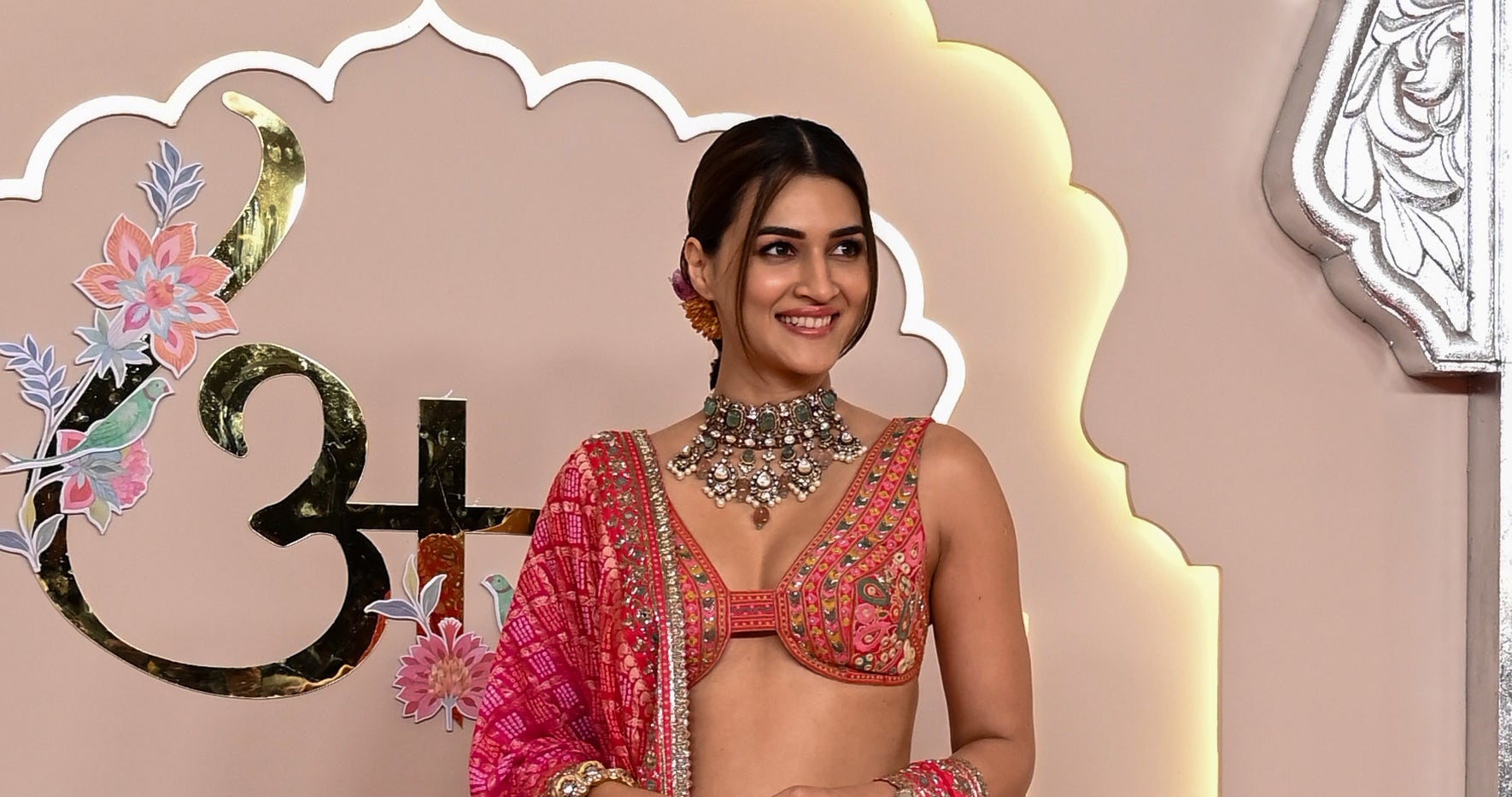 Kriti in an ornate traditional outfit including a lehenga and jewelry, posing on a decorative stage