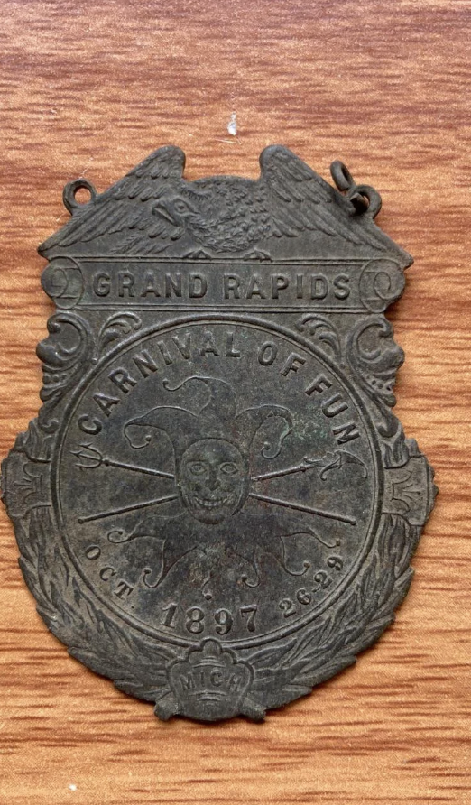 Antique medal from the Grand Rapids Carnival of Fun, dated Oct 26-29, 1897, featuring an ornate design with a face and crossed objects