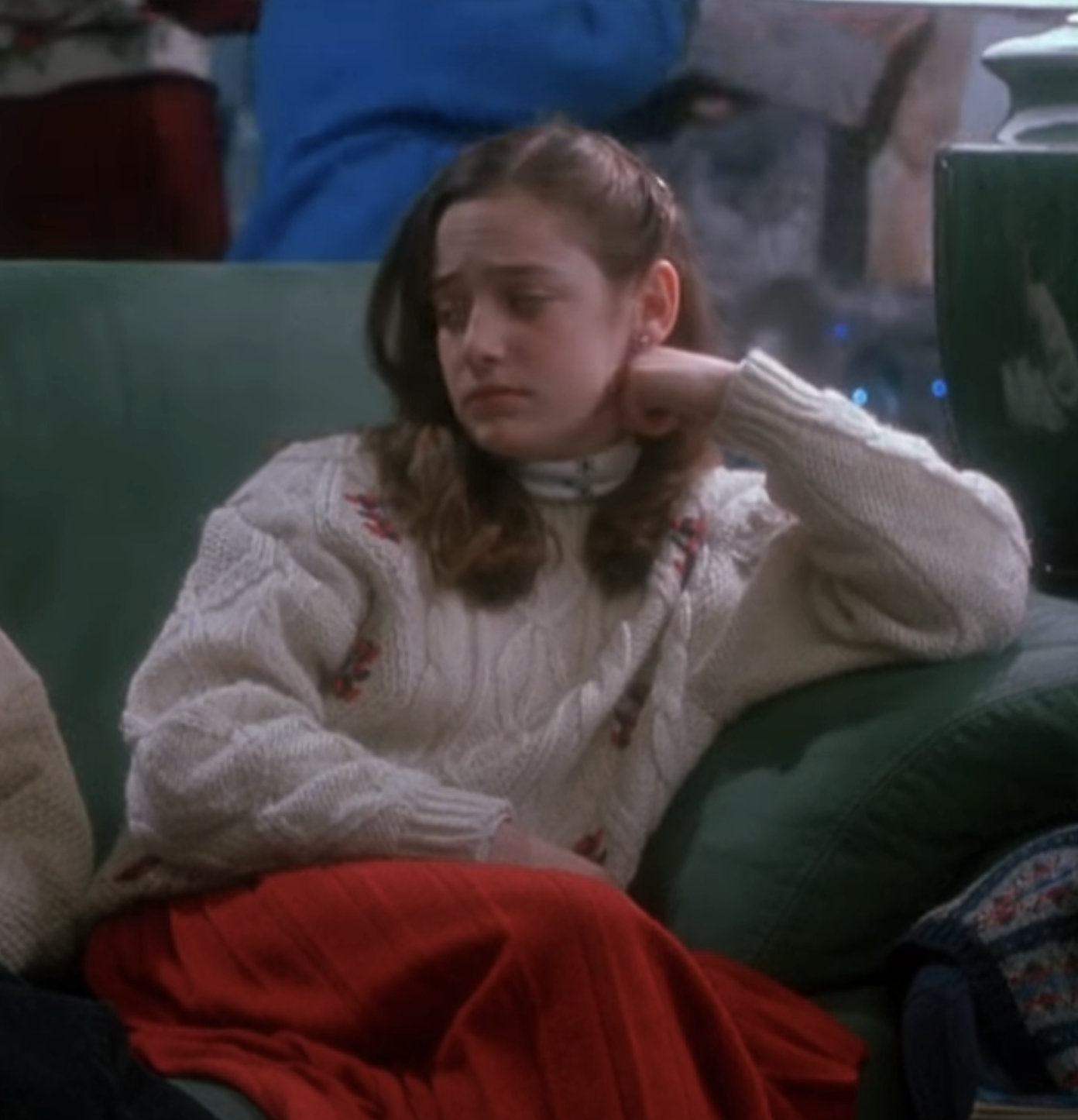 Megan sitting on a couch wearing a knitted sweater in a scene