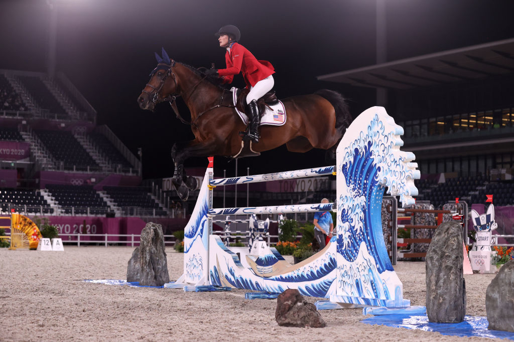 Olympic equestrian Jessica Springsteen rides a horse in a show jumping event at Tokyo 2020 Olympics. The horse clears an obstacle with wave design