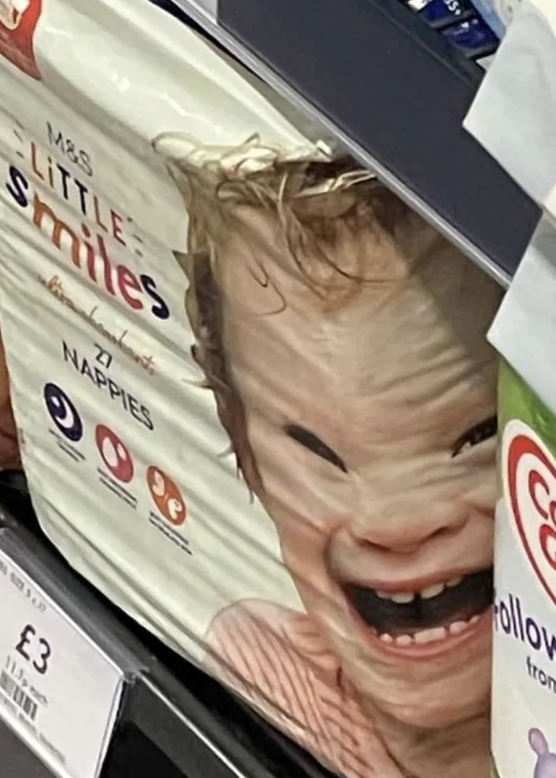 Baby diaper packaging with a distorted image of a laughing baby due to package compression, spotted on a store shelf. Price tag shows £3