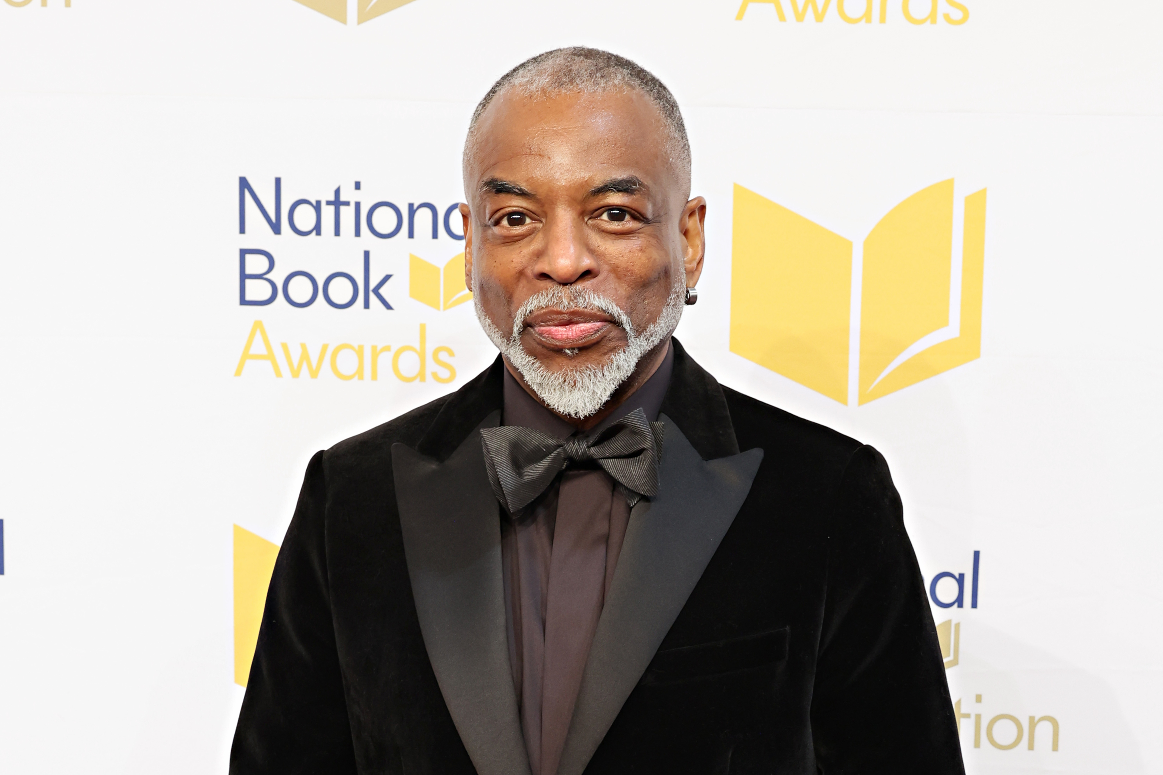 LeVar Burton stands on the red carpet at the National Book Awards, wearing a black velvet tuxedo with a black bow tie