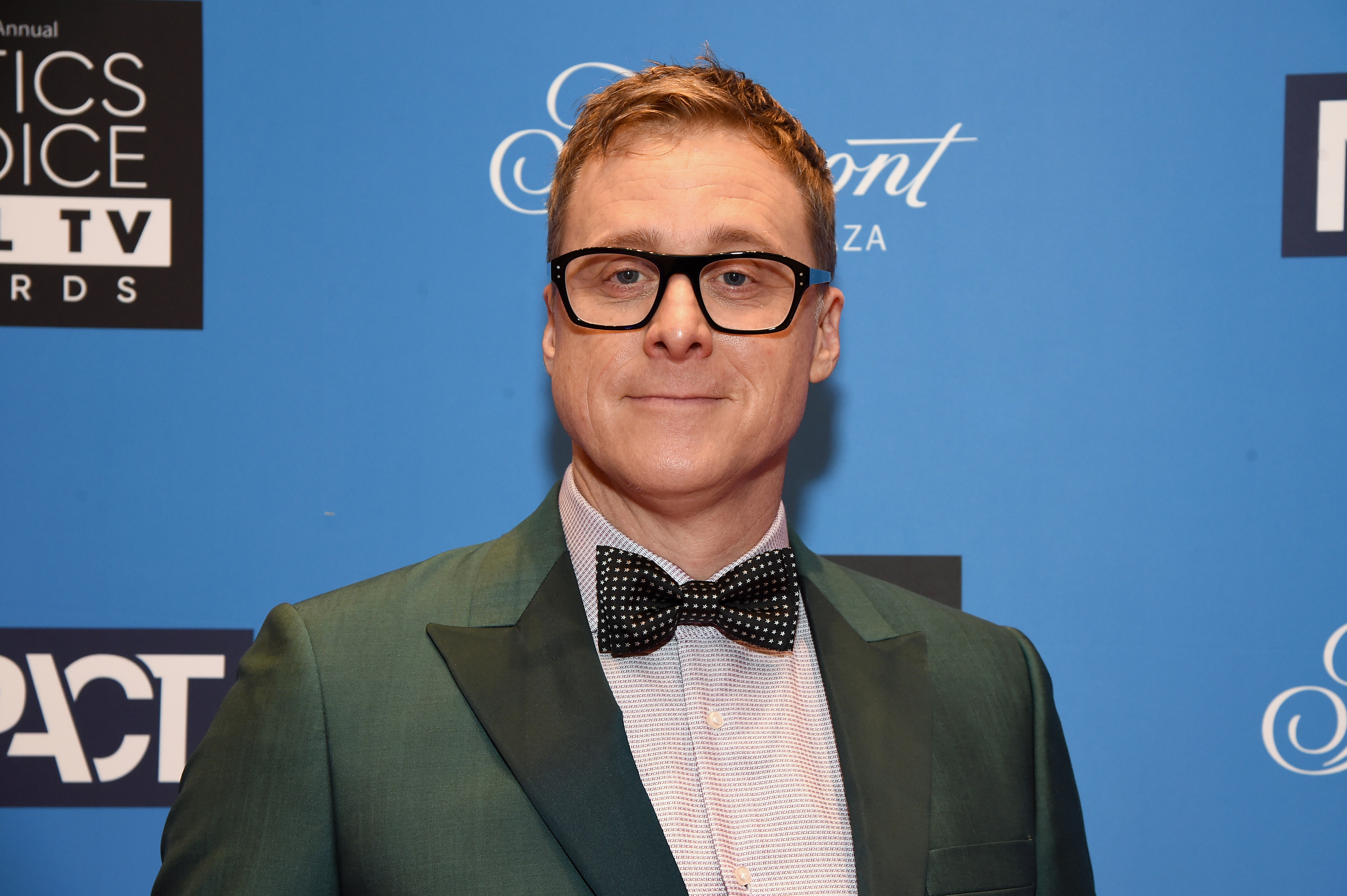 Alan Tudyk at the Critics' Choice Television Awards, wearing a classic suit and bow tie, posing in front of a step-and-repeat event backdrop