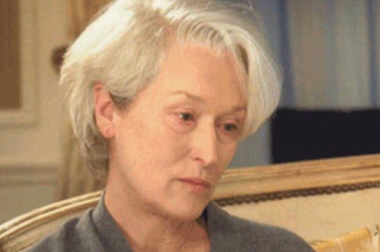 Meryl Streep with a thoughtful expression, seated indoors