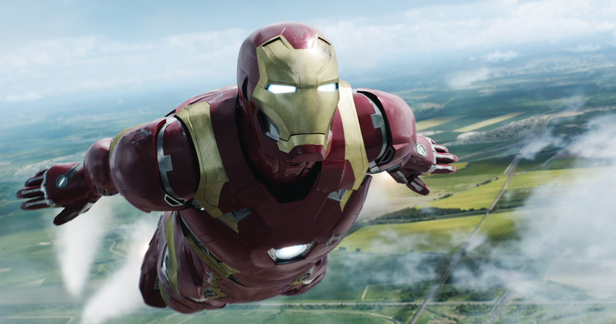 Iron Man, in his signature red and gold suit, flies over a landscape with fields below him in a scene from "Captain America: Civil War"