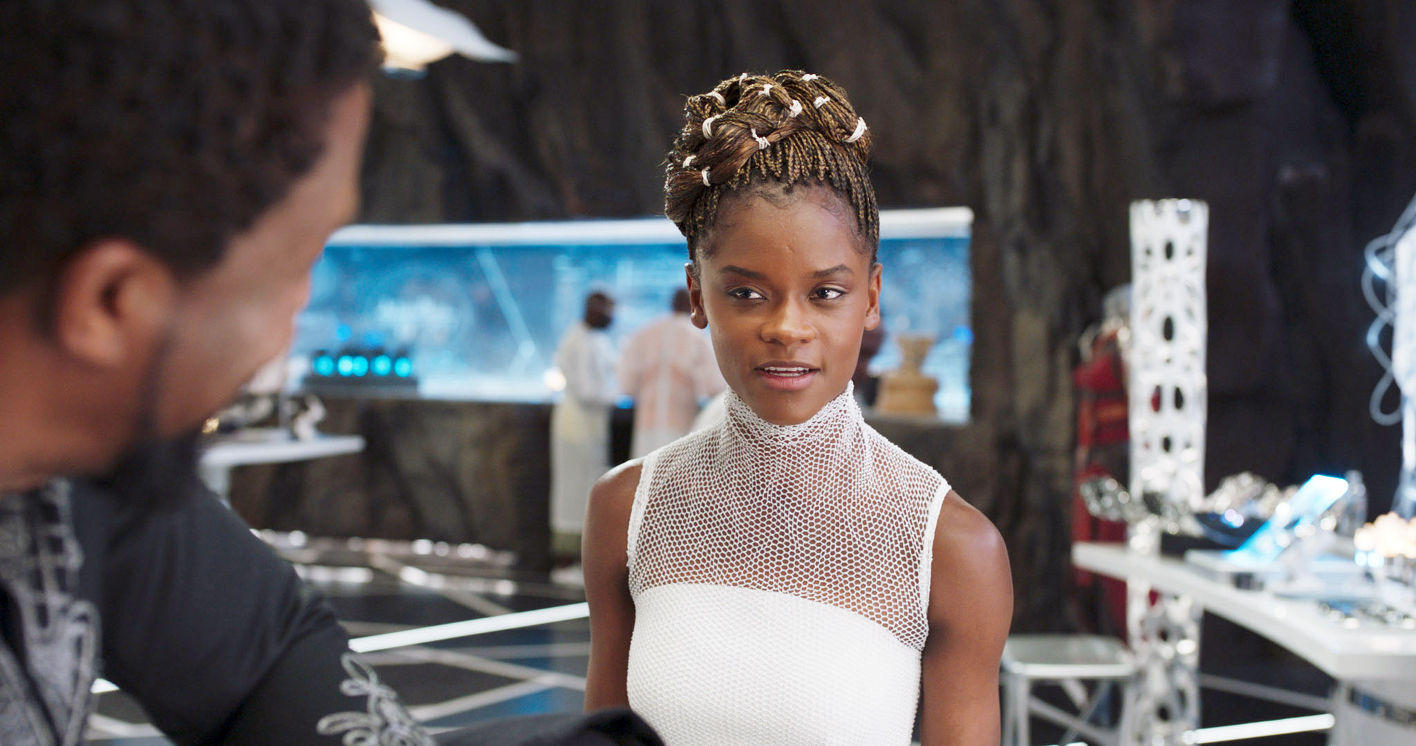 Letitia Wright is wearing a white outfit while talking to Chadwick Boseman in a scene from "Black Panther"