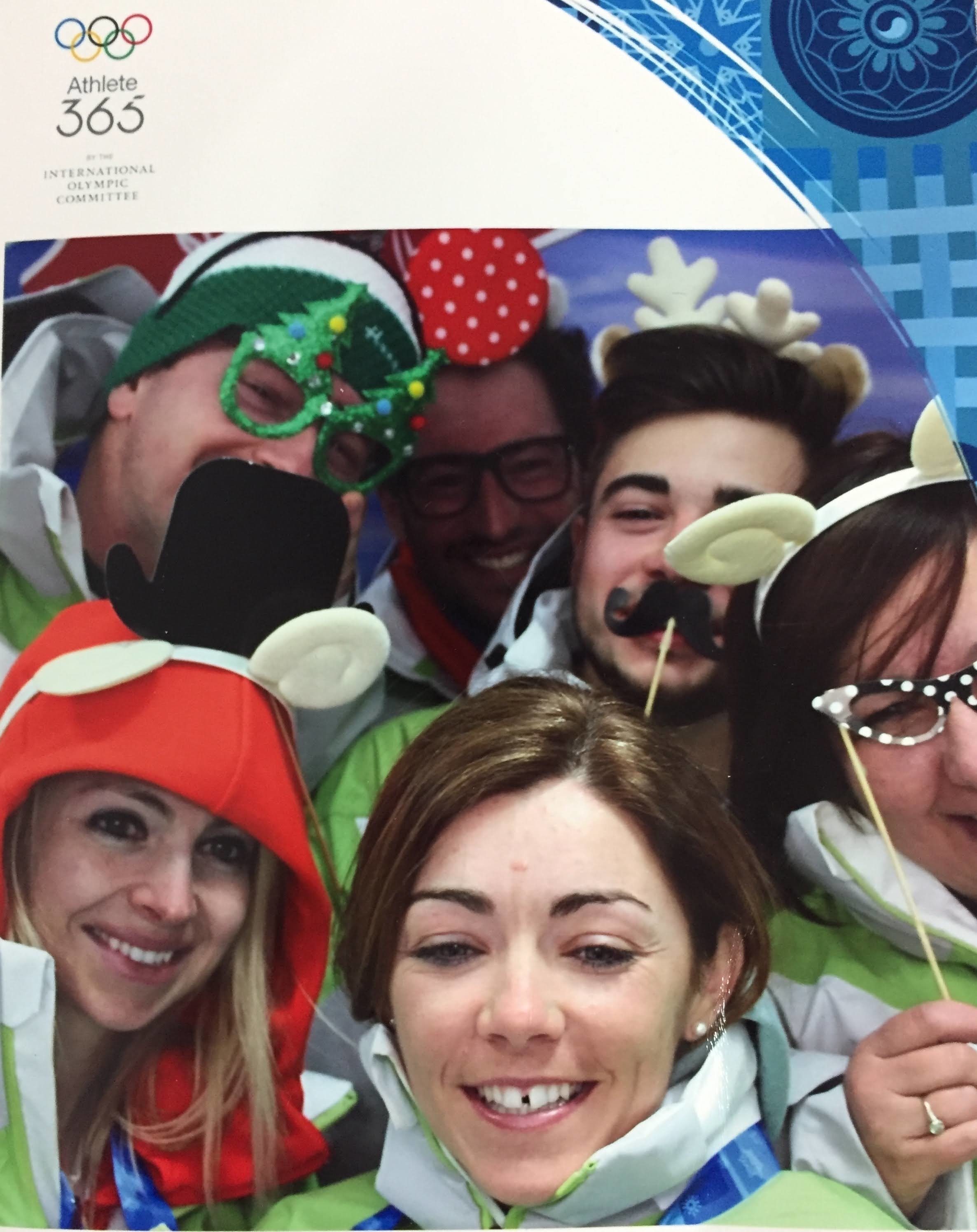 Group photo of people at an event wearing various festive accessories and costumes, like glasses and hats. The image features five unnamed individuals