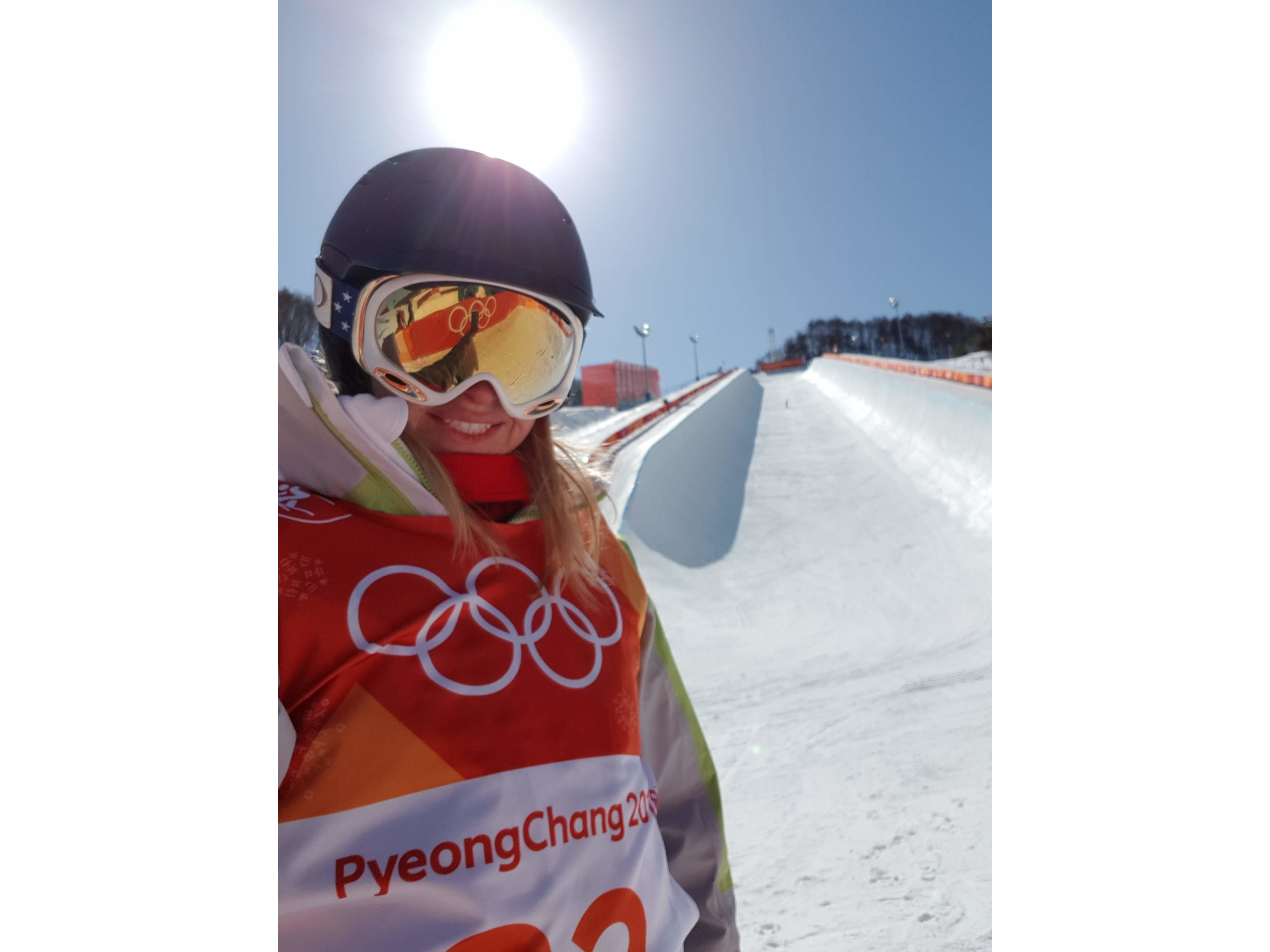 Elizabeth in ski gear with a helmet and goggles stands in front of a snowy slope at PyeongChang 2018 Winter Olympics