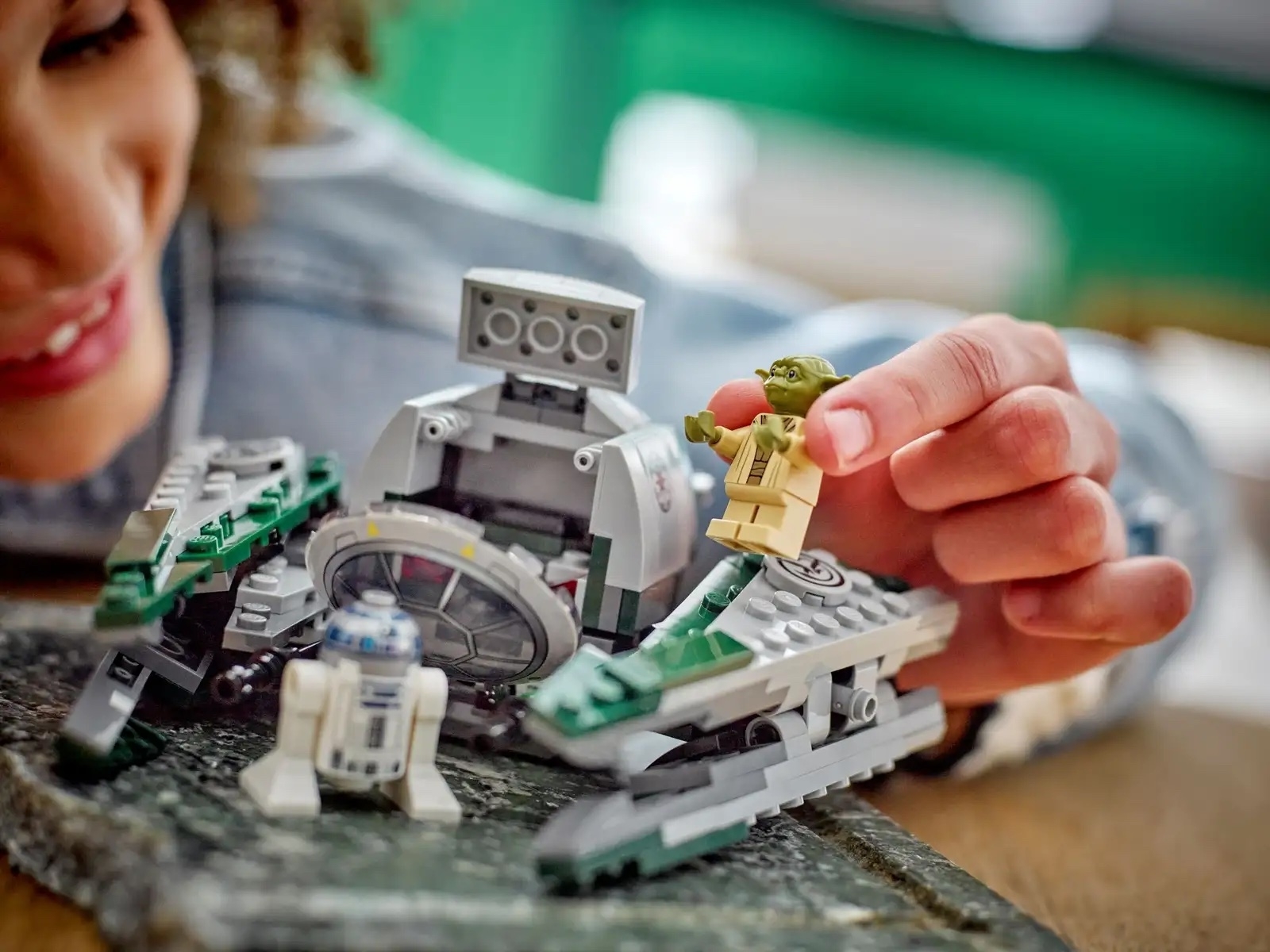 Person playing with Lego figures of Yoda and R2-D2 from Star Wars