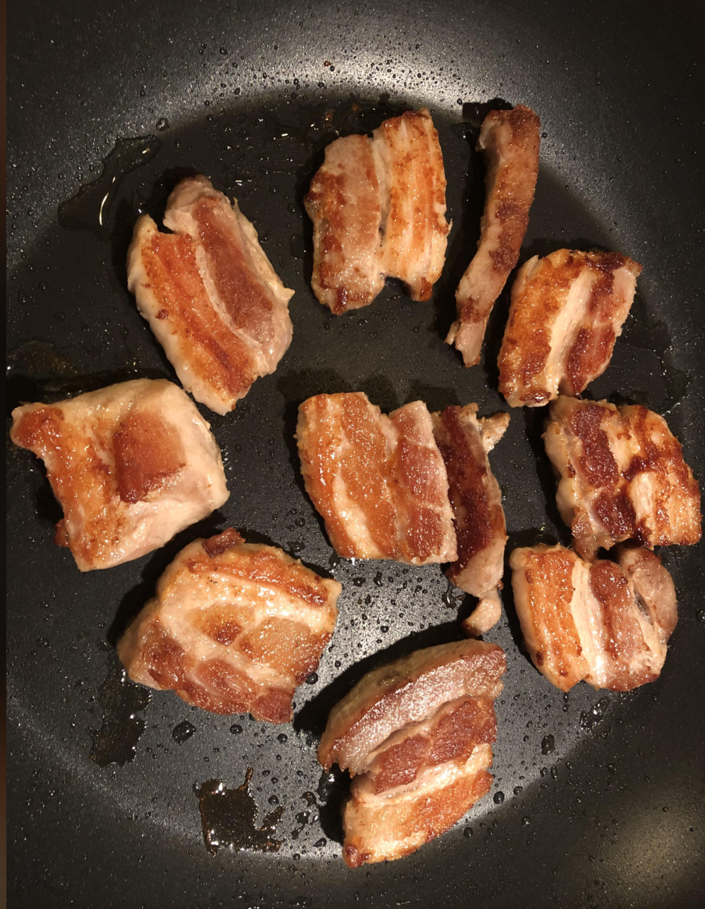 Bacon pieces sizzling in a frying pan
