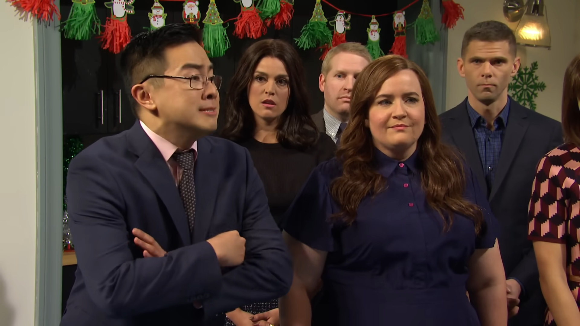 Bowen Yang, Cecily Strong, Beck Bennett, Aidy Bryant, Alex Moffat, and another person stand together, appearing attentive at a formal gathering