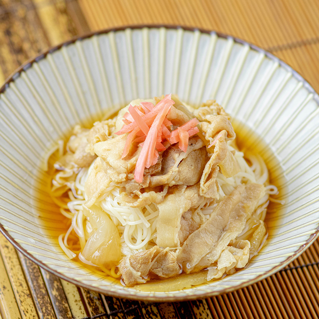 器に盛られた素麺の上に薄切りの肉と刻んだしょうががのせられた料理。