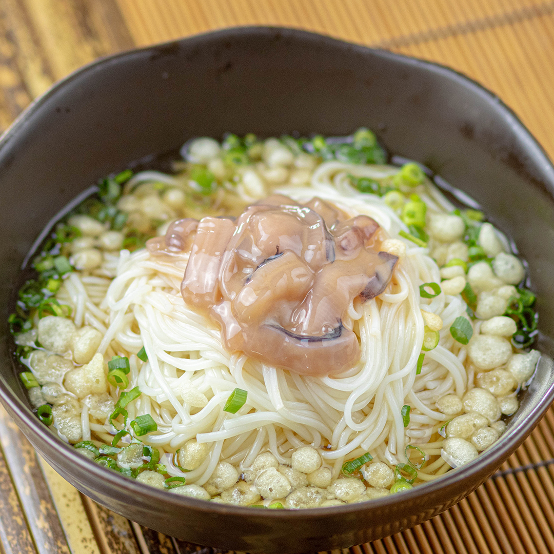 器に盛られた麺料理。青ネギ、揚げ玉、イカの塩辛がトッピングされている。
