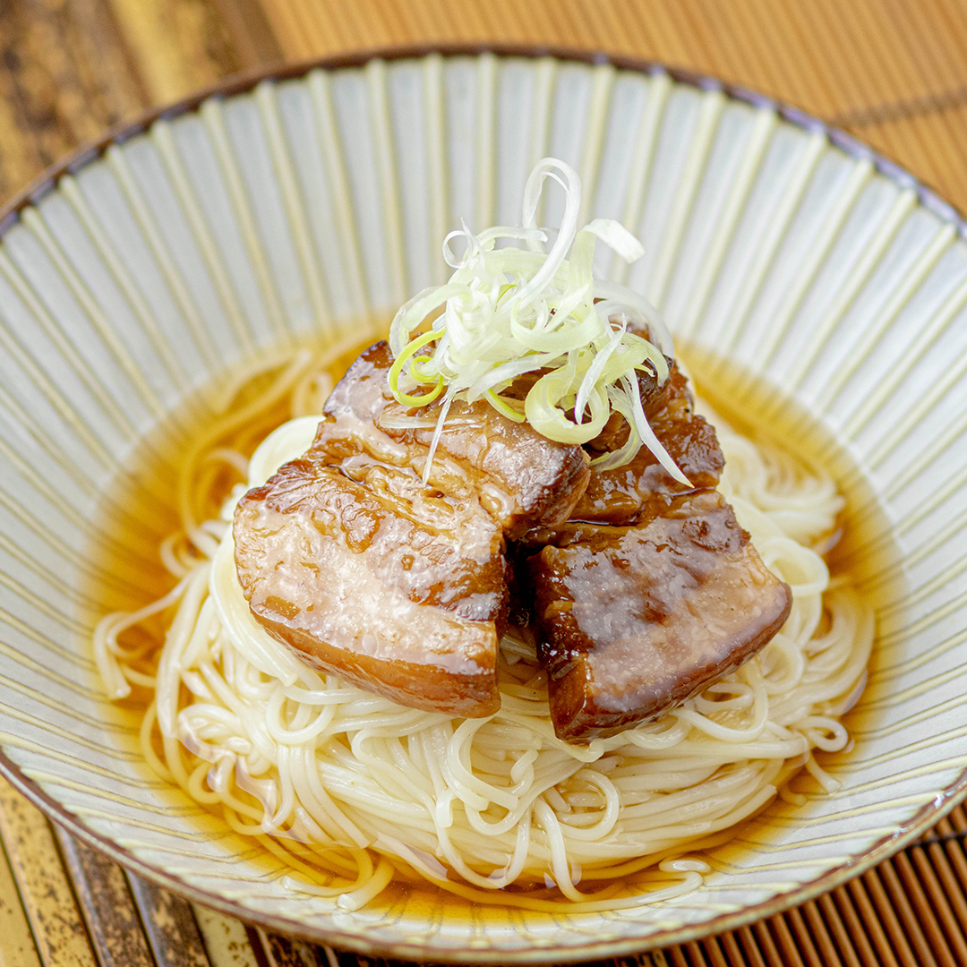 器に入った麺の上に、煮豚とネギが乗っています。