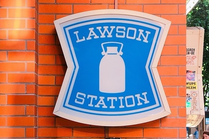 ローソンの店舗看板。「LAWSON STATION」と書かれた青と白の看板が24時間営業を示している。