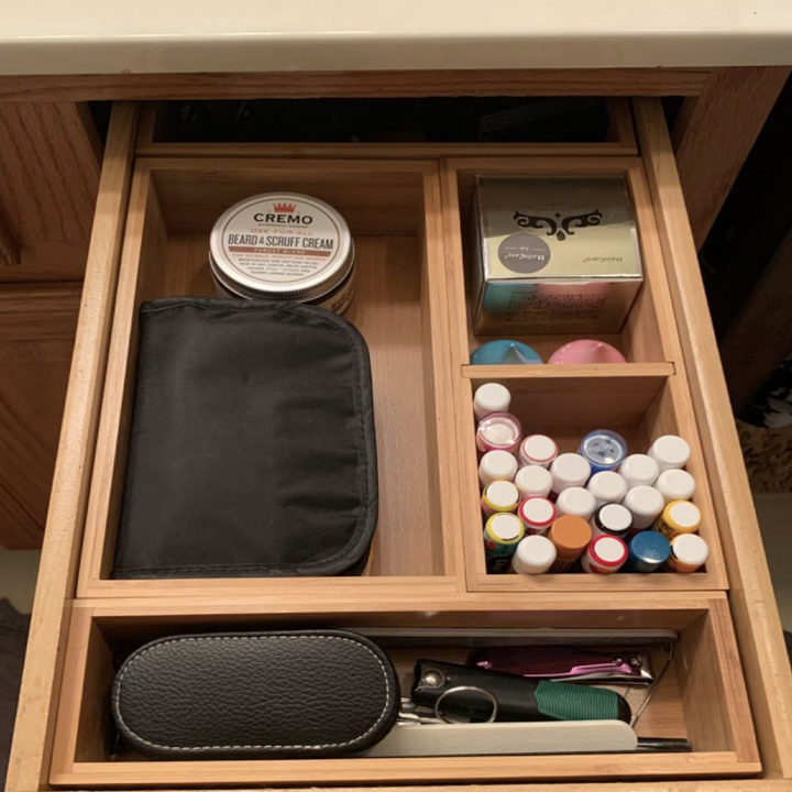 A well-organized drawer with grooming products, including a beard and scrub cream, nail clippers, nail polish bottles, a manicure set, and a grooming kit