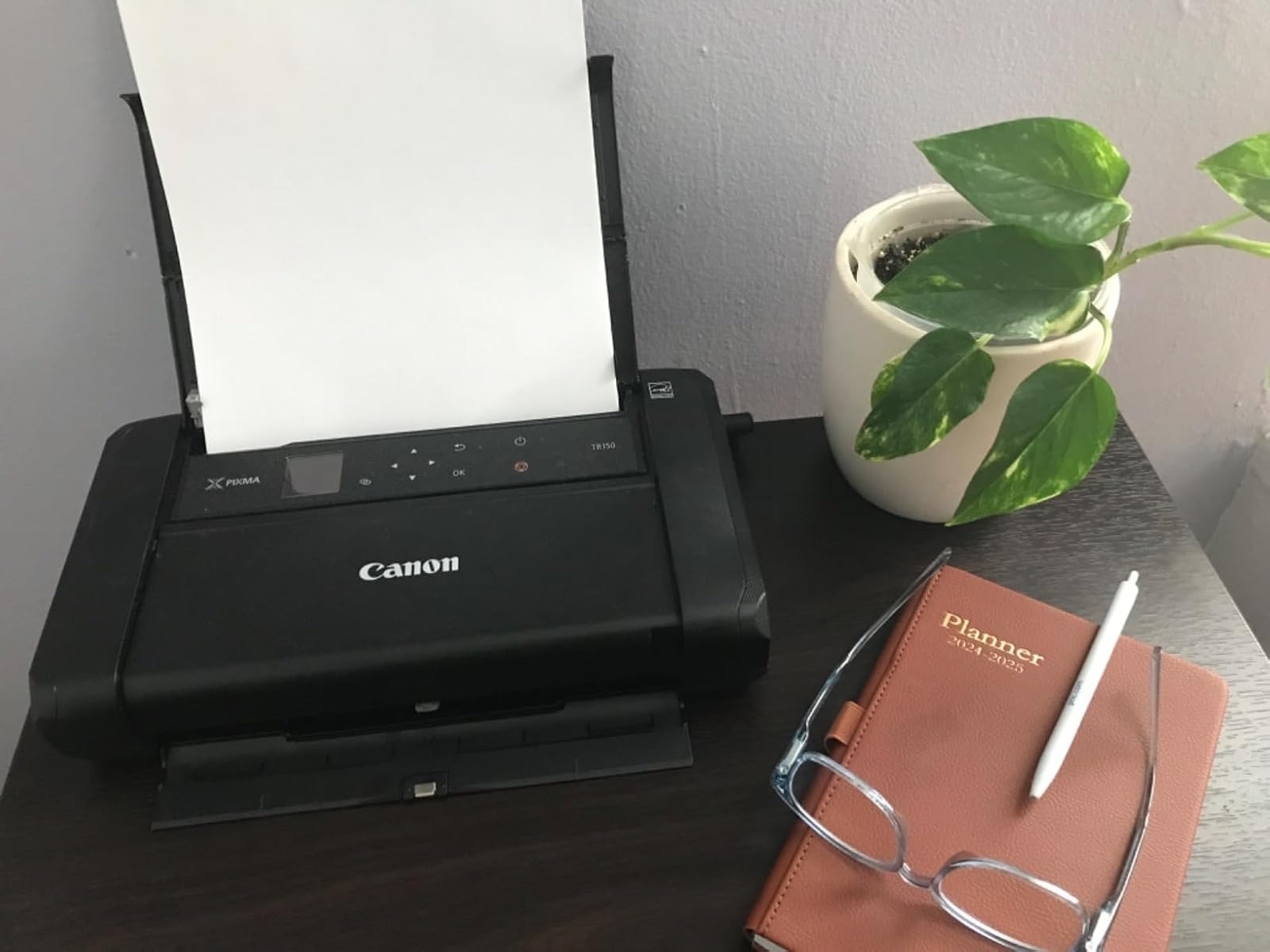 A portable Canon printer with a sheet of paper in it