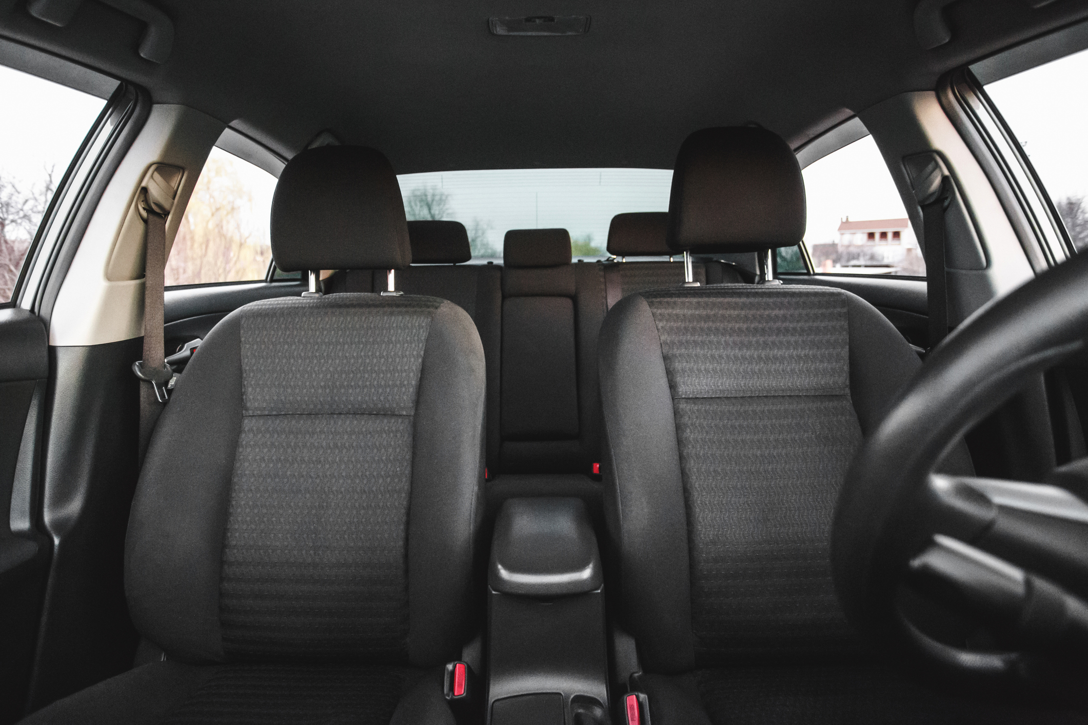 Interior of a car with two front seats, a center console, back seats, and a steering wheel