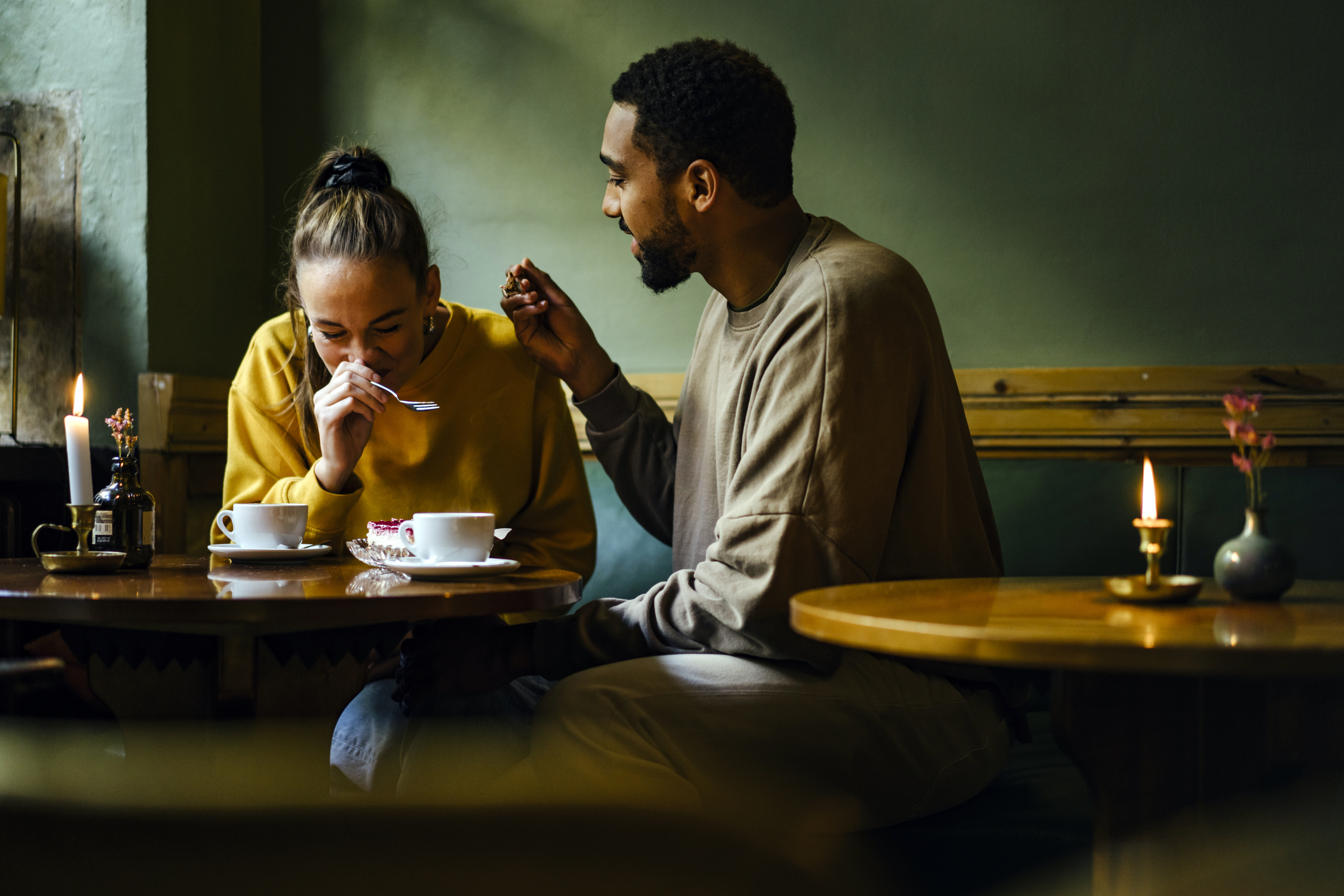 Man and woman sitting at a café, sharing a dessert and laughing