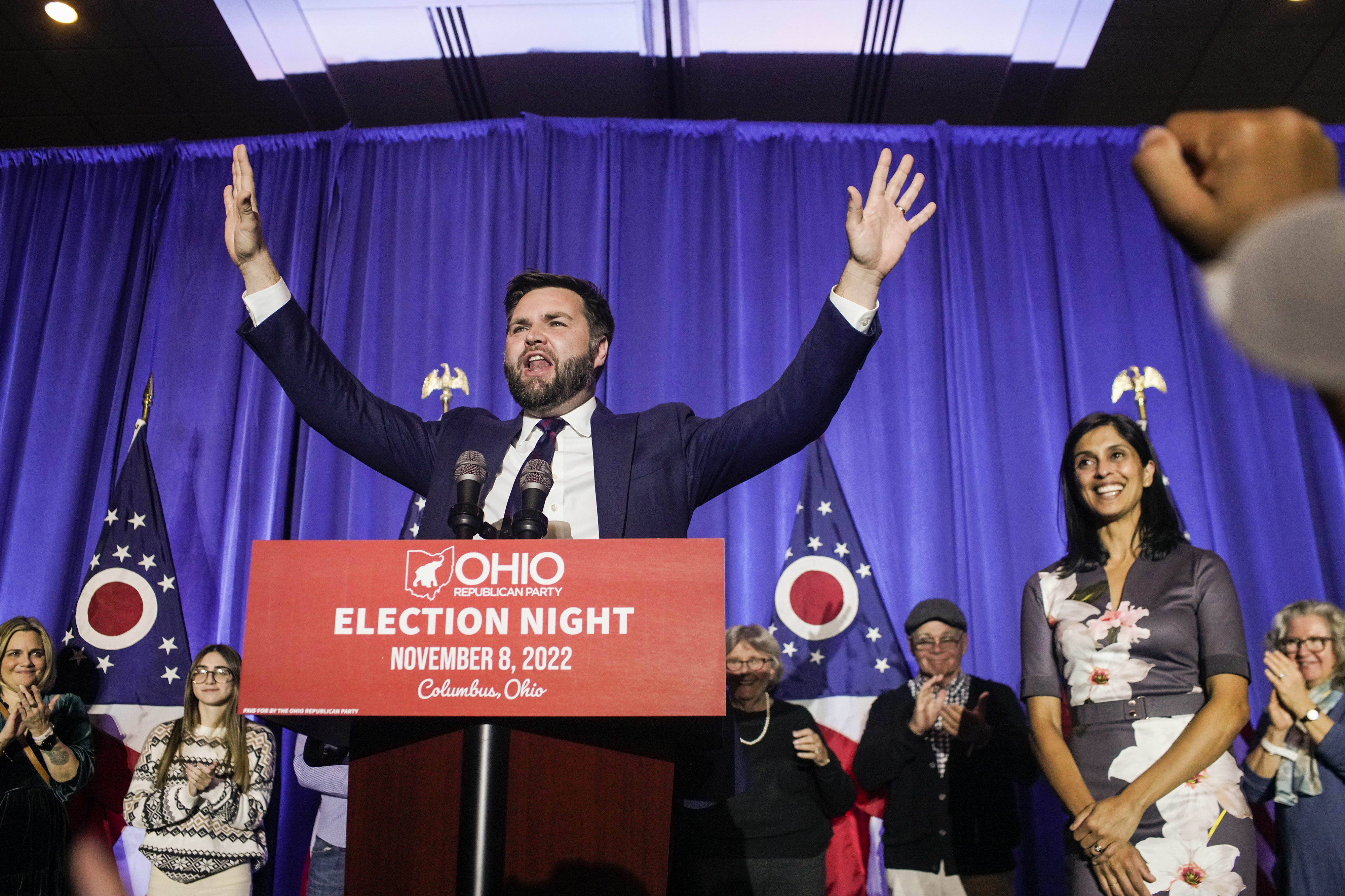J.D. Vance celebrates on stage at Ohio GOP Election Night event, November 8, 2022, in Columbus, Ohio, with supporters and Erika Vance nearby