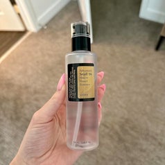 A hand holding a bottle of Cosrx Advanced Snail 96 Mucin Power Essence