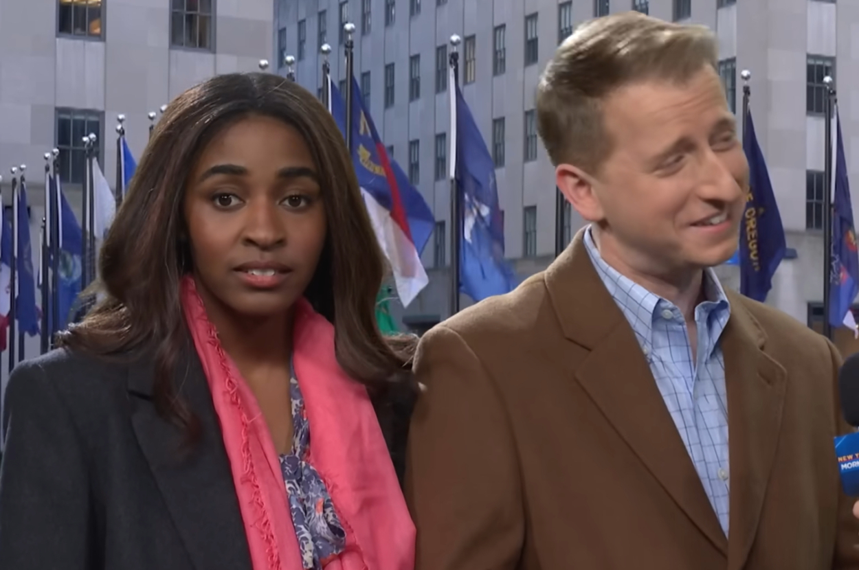 Ayo Edebiri with a pink scarf and James Austin Johnson in a brown blazer being interviewed in front of Rockefeller Center in an SNL skit