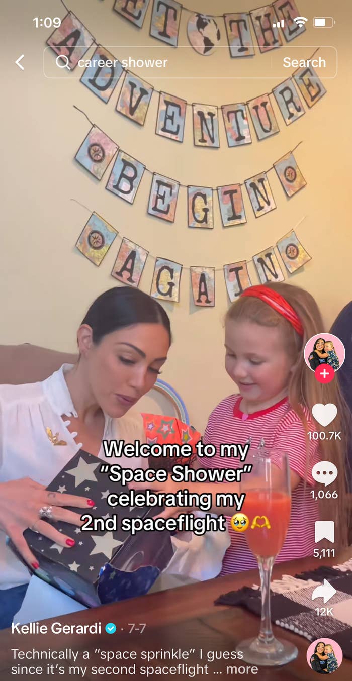 Kellie Gerardi and a child are celebrating her second spaceflight with a "space shower." A banner reads "Let the Adventure Begin Again."