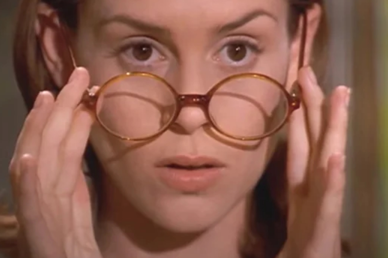 Woman adjusting round glasses, focused expression